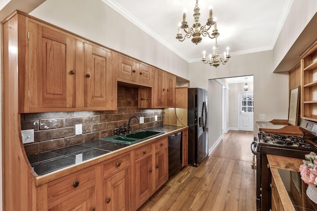 kitchen with a chandelier, ornamental molding, light wood-style flooring, black appliances, and a sink