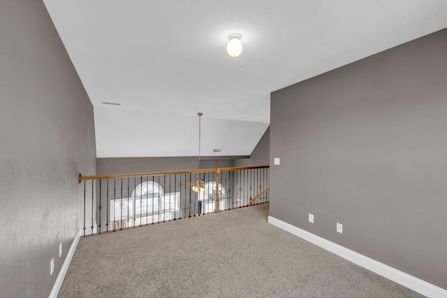 carpeted empty room with vaulted ceiling and baseboards