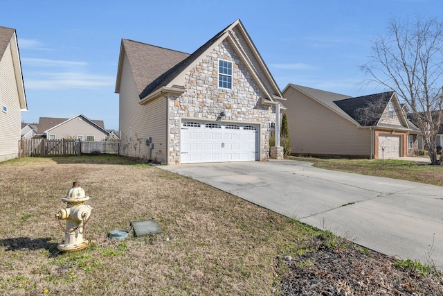 view of side of property featuring stone siding, driveway, a yard, and fence