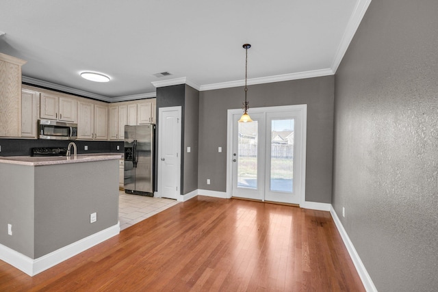 kitchen featuring baseboards, light wood-type flooring, appliances with stainless steel finishes, and ornamental molding