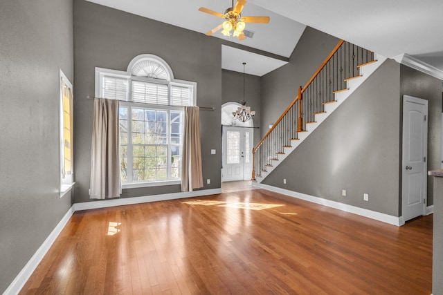 foyer entrance with stairway, a towering ceiling, baseboards, and wood-type flooring