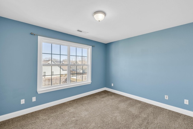 carpeted empty room featuring baseboards and visible vents