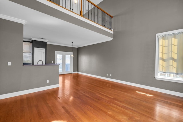 empty room featuring crown molding, baseboards, and wood finished floors