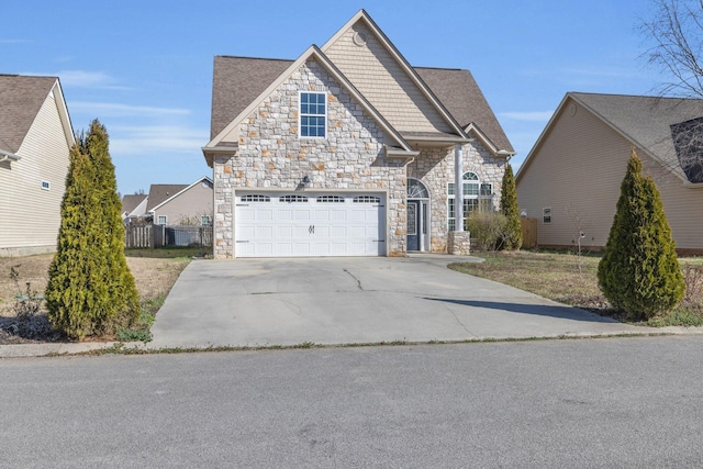 view of front facade featuring stone siding, driveway, an attached garage, and fence