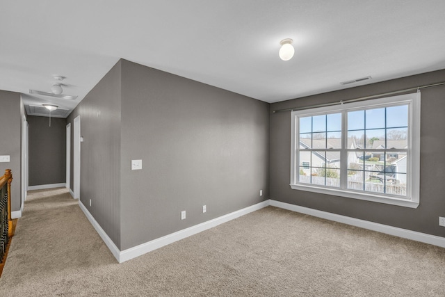 spare room with attic access, carpet flooring, baseboards, and visible vents