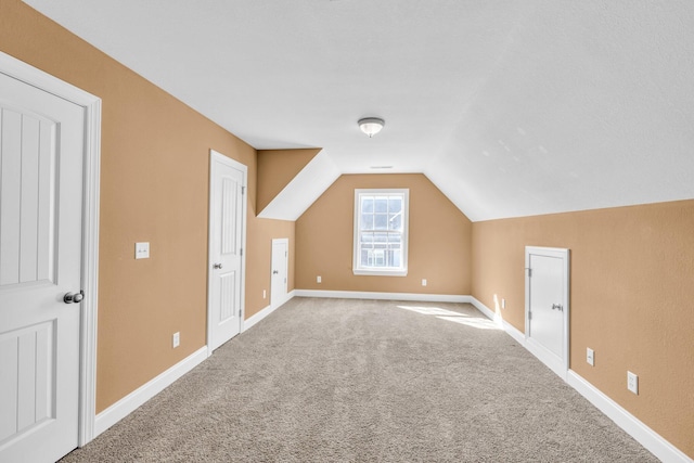 additional living space featuring baseboards, carpet floors, and vaulted ceiling