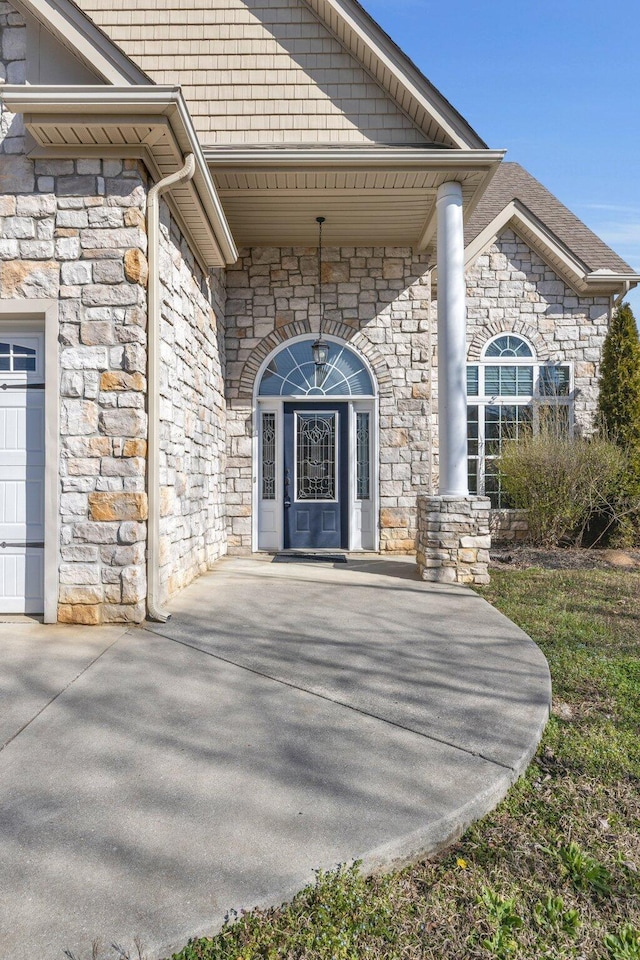 doorway to property with an attached garage and stone siding