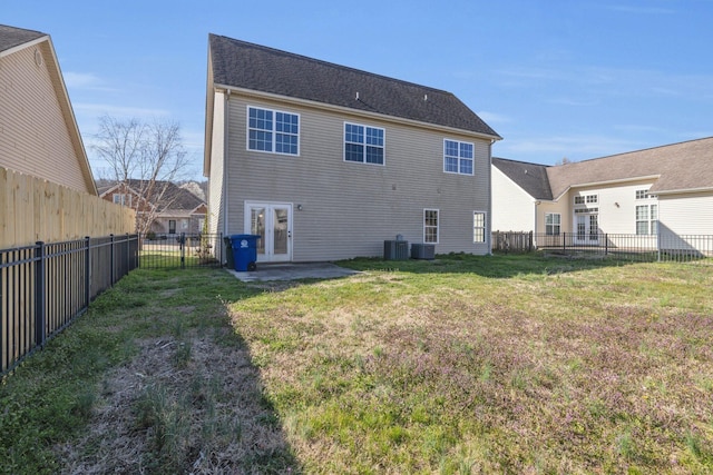 back of property with a fenced backyard, french doors, central AC, and a yard