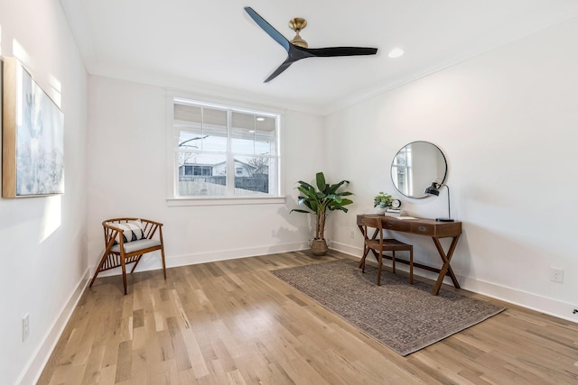 sitting room featuring ceiling fan, baseboards, wood finished floors, and crown molding