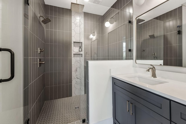 bathroom with visible vents, a shower stall, vanity, and tile walls