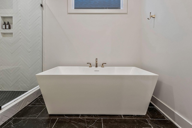 bathroom with a freestanding bath, baseboards, marble finish floor, and tiled shower