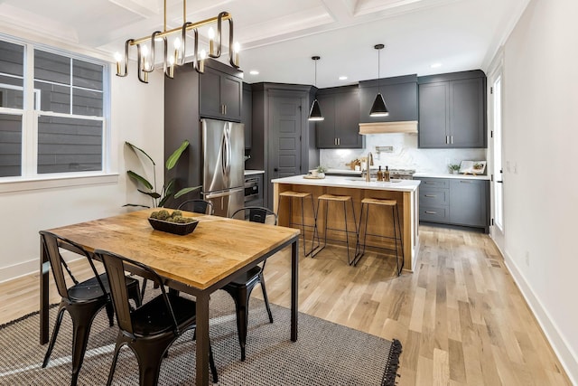 dining room with beam ceiling, a notable chandelier, coffered ceiling, light wood finished floors, and baseboards