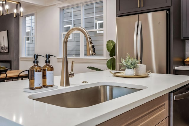 details with a sink, appliances with stainless steel finishes, and light countertops