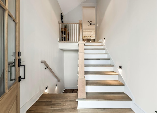 stairway featuring wood finished floors and vaulted ceiling