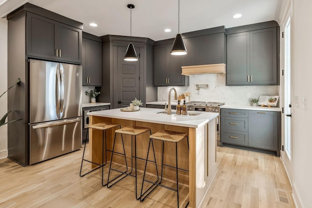 kitchen with visible vents, light wood finished floors, a sink, stainless steel appliances, and light countertops