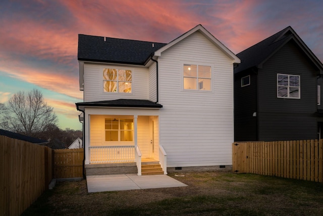 back of property at dusk featuring a shingled roof, a yard, a fenced backyard, and crawl space