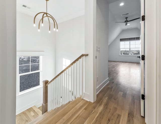 stairway with visible vents, ceiling fan with notable chandelier, baseboards, and wood finished floors