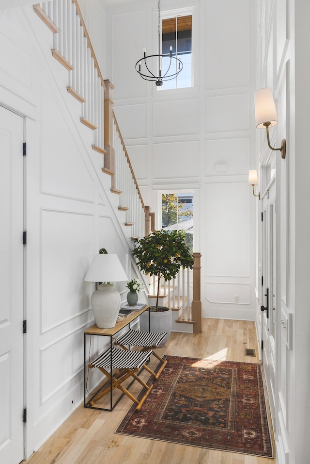 foyer featuring a decorative wall, light wood-type flooring, and a chandelier