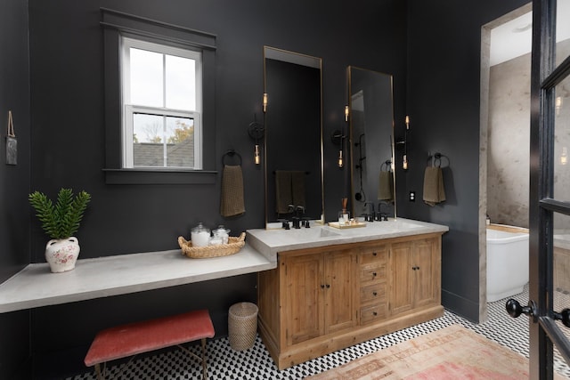 bathroom featuring double vanity, a freestanding tub, and a sink