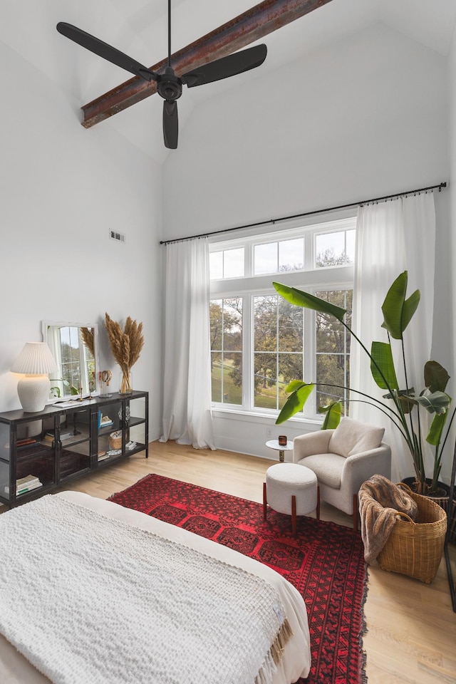 bedroom featuring beamed ceiling, high vaulted ceiling, a ceiling fan, and wood finished floors