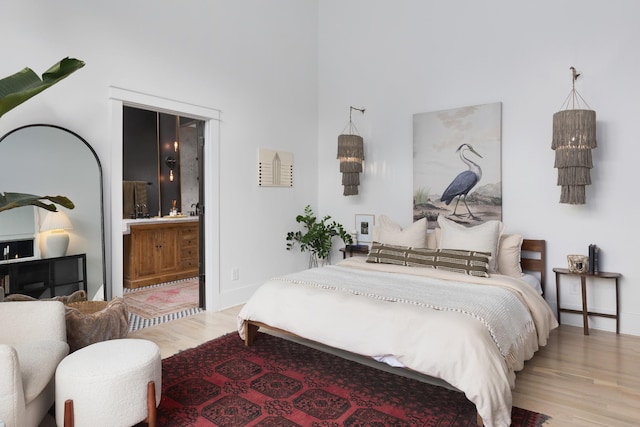 bedroom with connected bathroom, baseboards, and wood finished floors