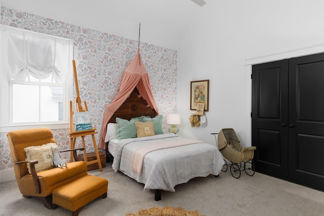 carpeted bedroom with wallpapered walls, lofted ceiling, and a closet