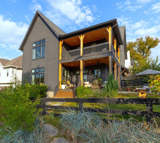 rear view of house featuring a patio, a balcony, and a fenced front yard