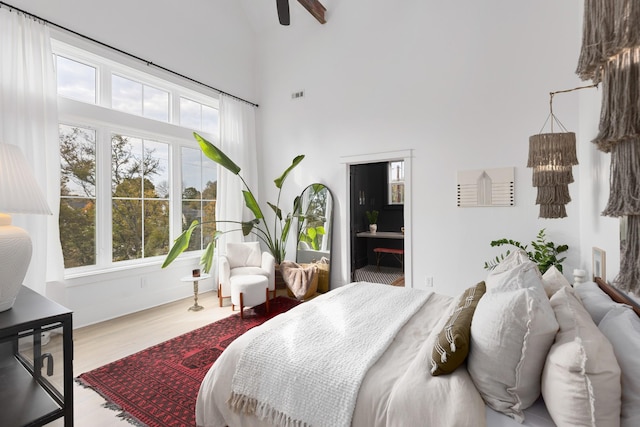 bedroom featuring visible vents, a towering ceiling, and wood finished floors