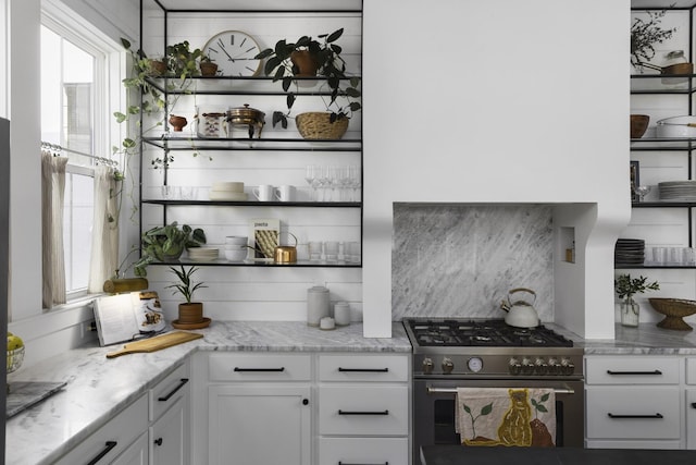 kitchen featuring white cabinets, light stone countertops, stainless steel stove, and open shelves