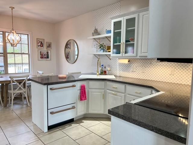 kitchen featuring an inviting chandelier, a peninsula, open shelves, a sink, and pendant lighting