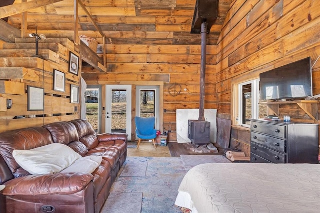 bedroom with multiple windows, a high ceiling, access to exterior, and a wood stove