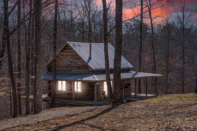 view of front of property featuring a view of trees, covered porch, and metal roof