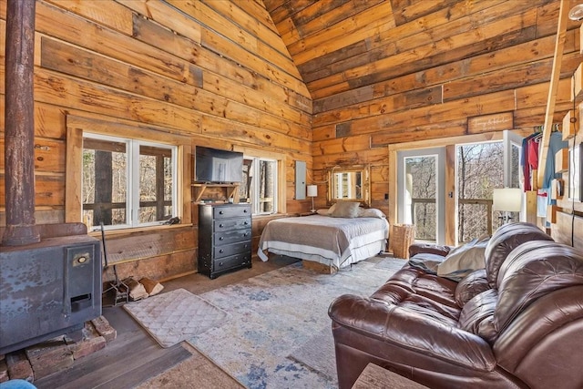 bedroom featuring high vaulted ceiling, wood walls, and a wood stove