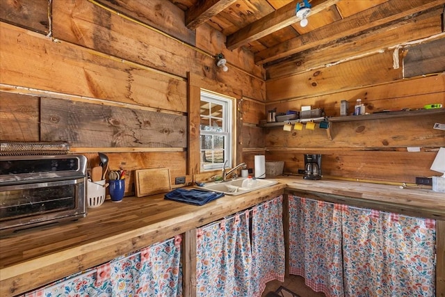 interior space featuring a toaster, wood walls, wood ceiling, beam ceiling, and a sink