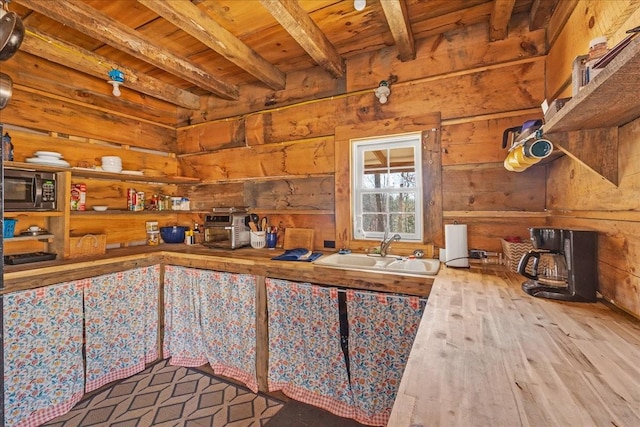 kitchen with stainless steel microwave, beamed ceiling, wood ceiling, wood finished floors, and a sink