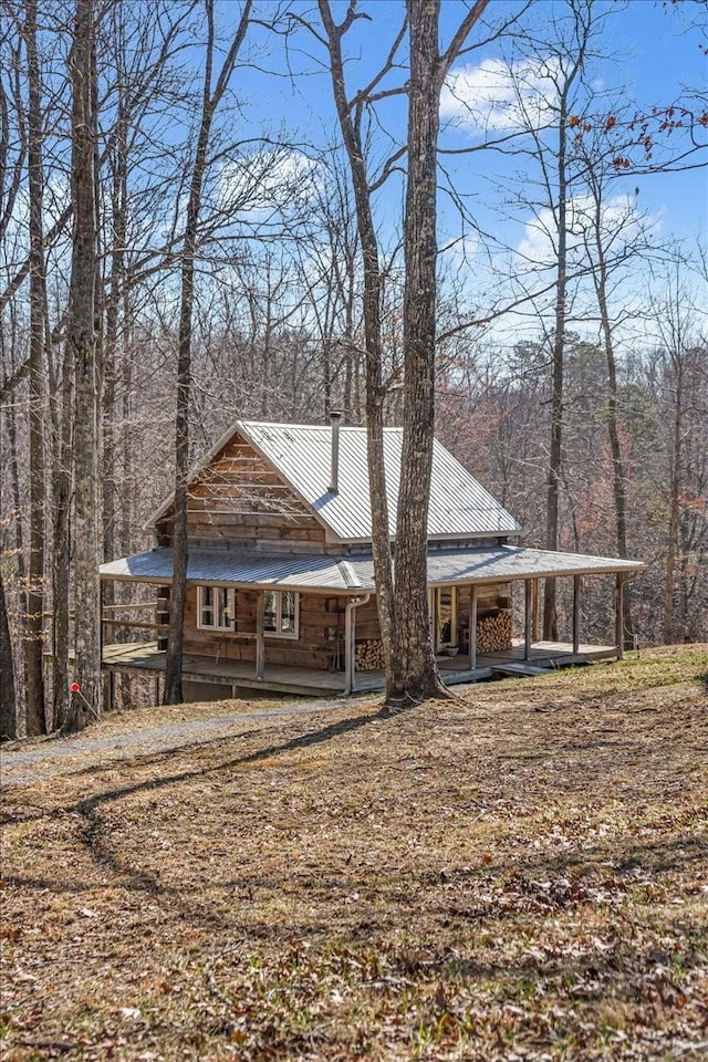 view of front of home with metal roof, a view of trees, and a carport