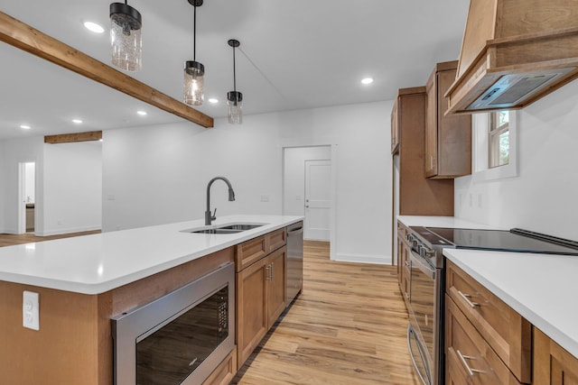 kitchen with a sink, brown cabinetry, light wood-type flooring, and stainless steel appliances