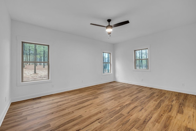 spare room with a ceiling fan, light wood-style floors, visible vents, and baseboards