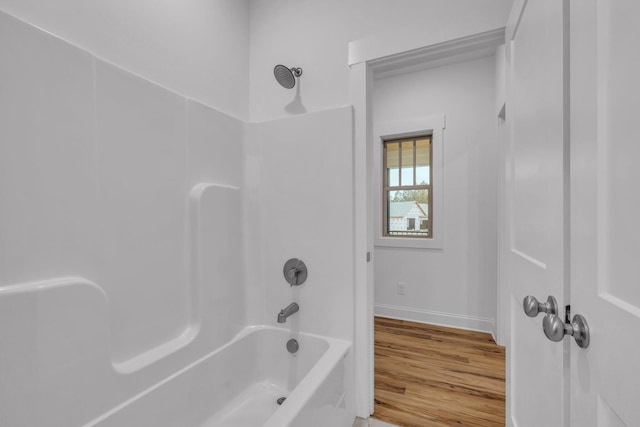 bathroom with shower / bathing tub combination, baseboards, and wood finished floors