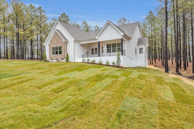 view of front facade featuring a porch, board and batten siding, a front lawn, and a shingled roof