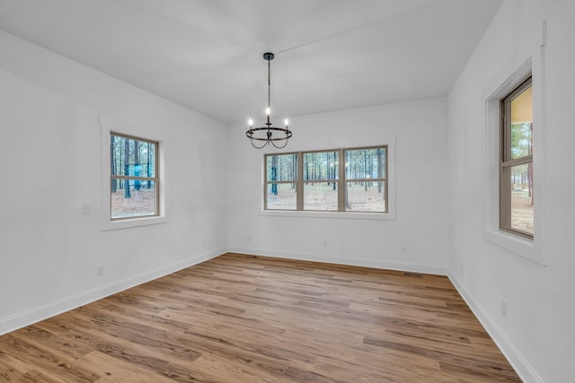 unfurnished room featuring a notable chandelier, light wood-style floors, and baseboards