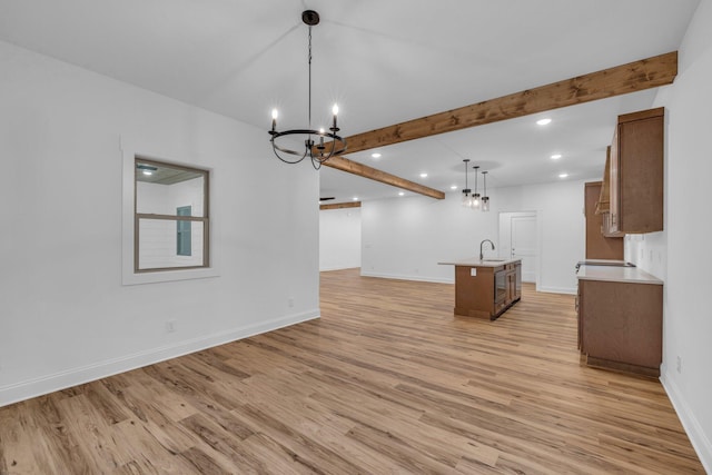 interior space featuring light wood-style floors, beam ceiling, a notable chandelier, and open floor plan