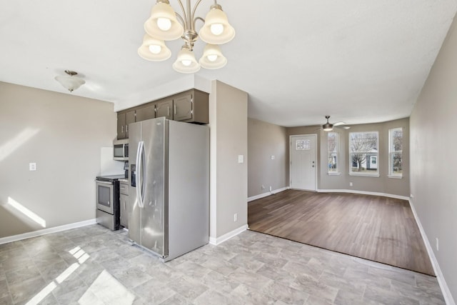 kitchen featuring ceiling fan with notable chandelier, decorative light fixtures, dark brown cabinetry, appliances with stainless steel finishes, and baseboards