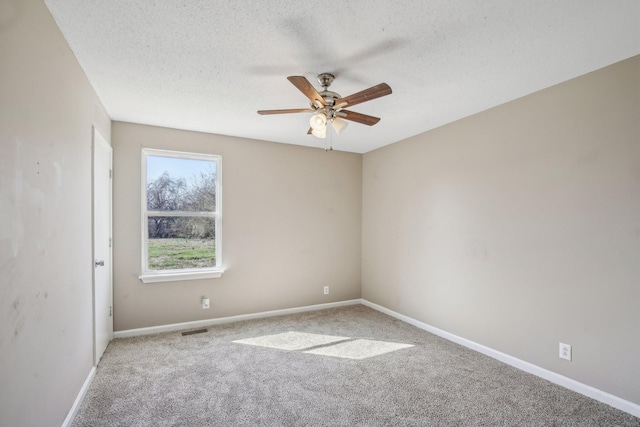 carpeted empty room with visible vents, baseboards, a textured ceiling, and ceiling fan