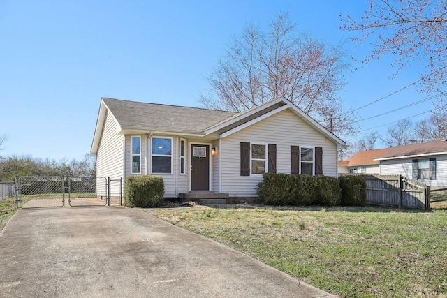 view of front of property featuring a front lawn, fence, concrete driveway, roof with shingles, and a gate