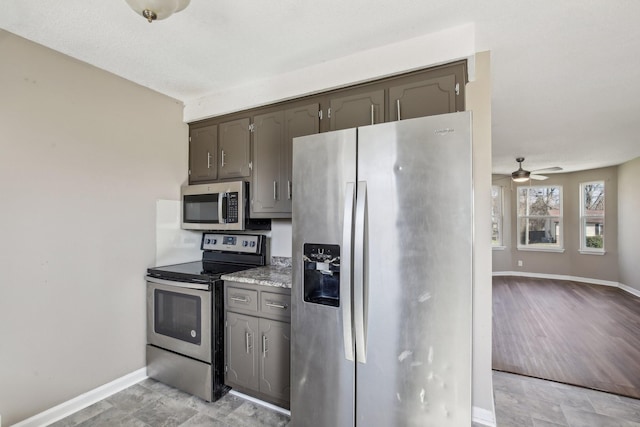 kitchen featuring a ceiling fan, baseboards, stainless steel appliances, light countertops, and dark brown cabinetry