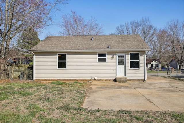 rear view of property featuring entry steps, a shingled roof, a patio, and fence