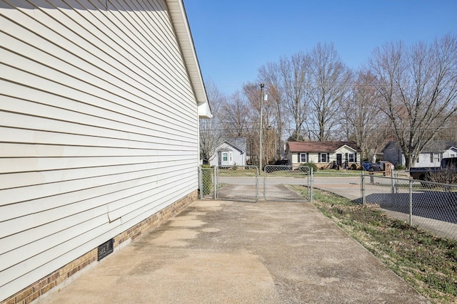 view of home's exterior with fence, driveway, and a gate