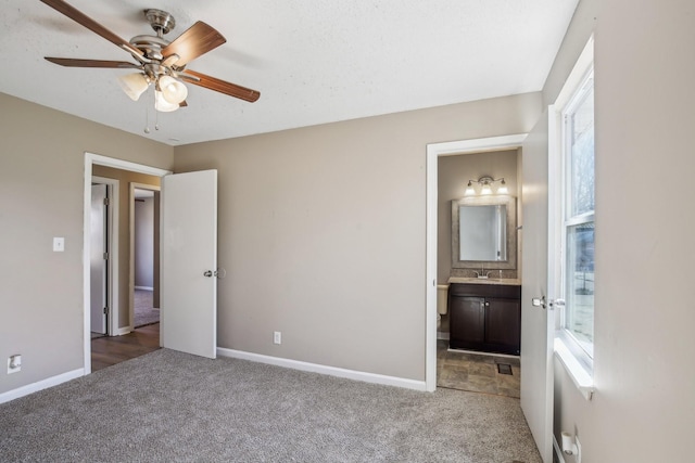 unfurnished bedroom featuring a sink, ensuite bath, baseboards, and carpet floors