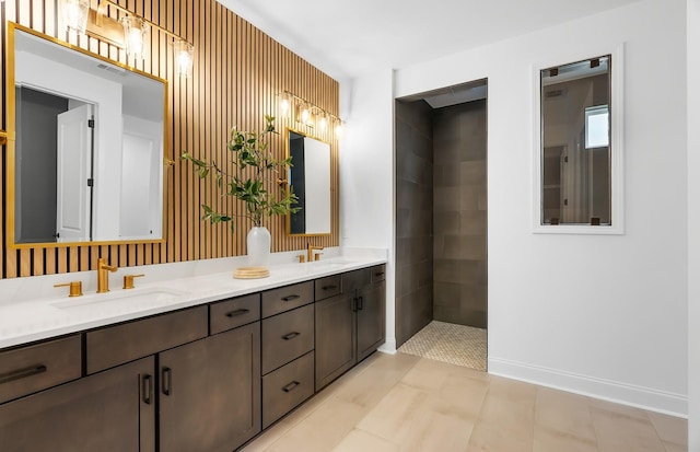 bathroom with a sink, baseboards, walk in shower, and double vanity